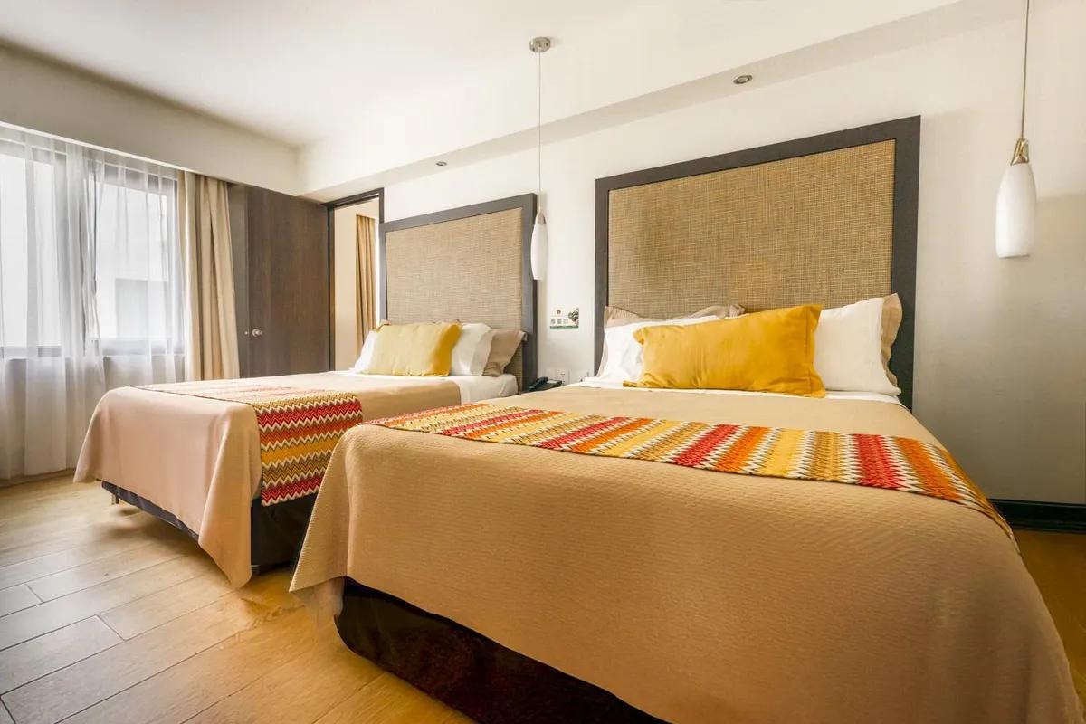 Family room from Hotel Catedral. Two double beds are visible. The colors are warm. Wooden floors.